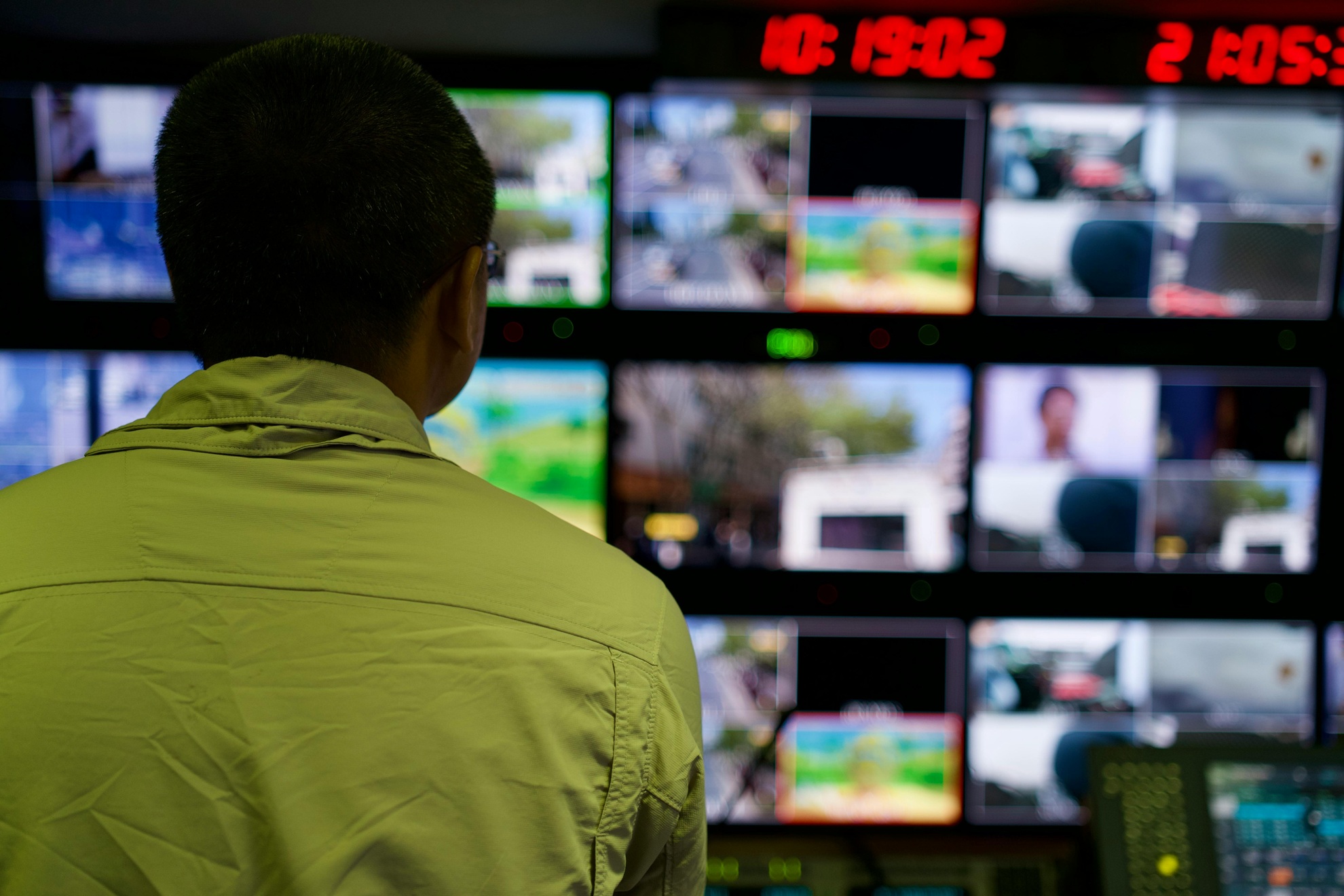 Image of aa man looking at a wall of security screens on a security system for video surveillance